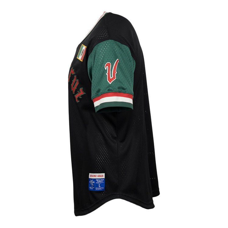 The EFF Veracruz Azules Vintage Inspired Replica V-Neck Mesh Jersey features a black body, green sleeves, red and white trim, a white V patch on the sleeve, plus additional patches on the shoulder and hem. Side view shown.