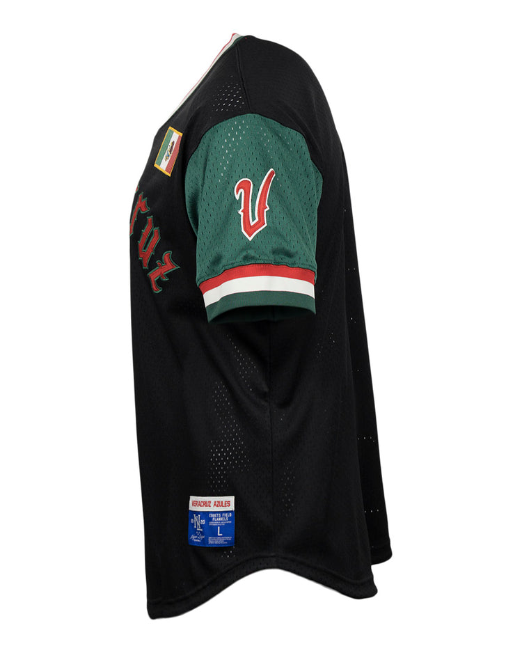 The EFF Veracruz Azules Vintage Inspired Replica V-Neck Mesh Jersey features a black body, green sleeves, red and white trim, a white V patch on the sleeve, plus additional patches on the shoulder and hem. Side view shown.