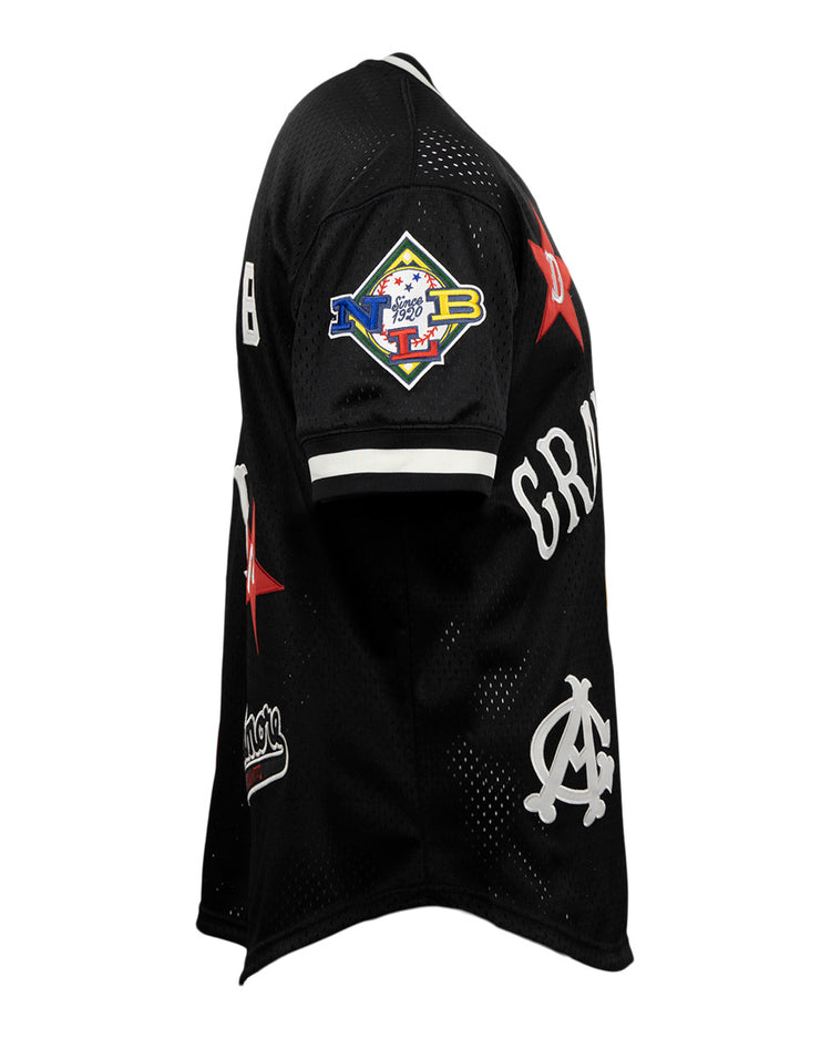 The EFF Negro League Allover Vintage Inspired NL Replica V-Neck Mesh Jersey in black features white accents, red stars, colorful patches—including a diamond-shaped sleeve patch—and stylized white lettering, reflecting classic Negro League Baseball mesh jersey style.