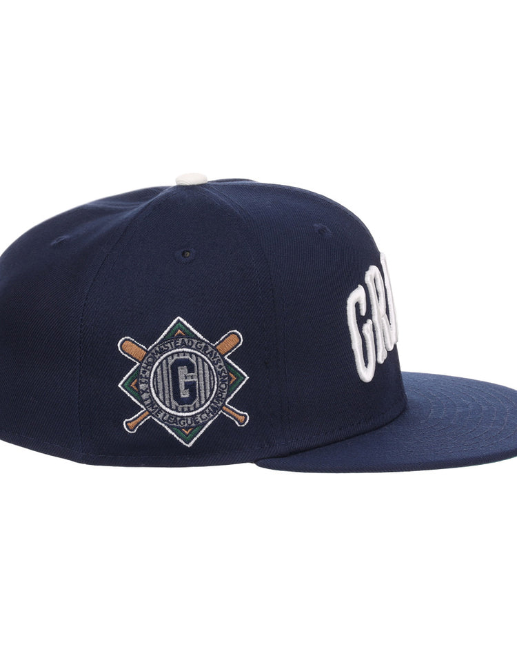 The EFF Homestead Grays NLB Flip Fitted Ballcap features a navy flat-brim, bold white GRD letters up front, and a diamond patch with bats and G logo on the side, honoring Pittsburgh’s legendary Homestead Grays.