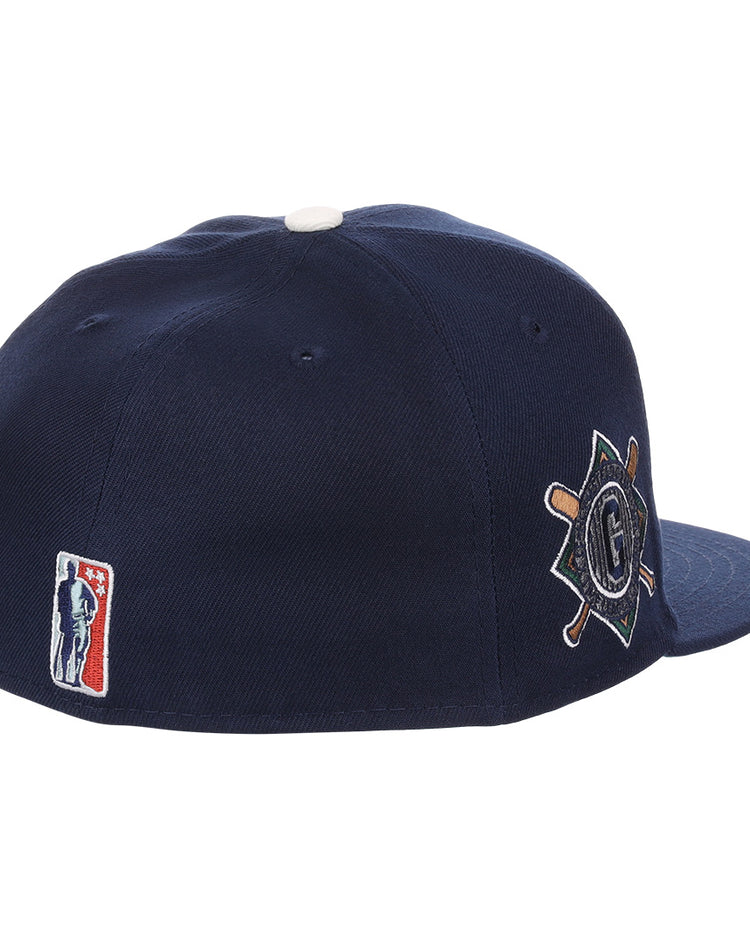 The EFF Homestead Grays NLB Flip Fitted Ballcap features dark blue fabric, a white top button, the classic MLB logo at the back, and a side patch with crossed bats and a “G” honoring Pittsburgh’s legendary Negro League team.