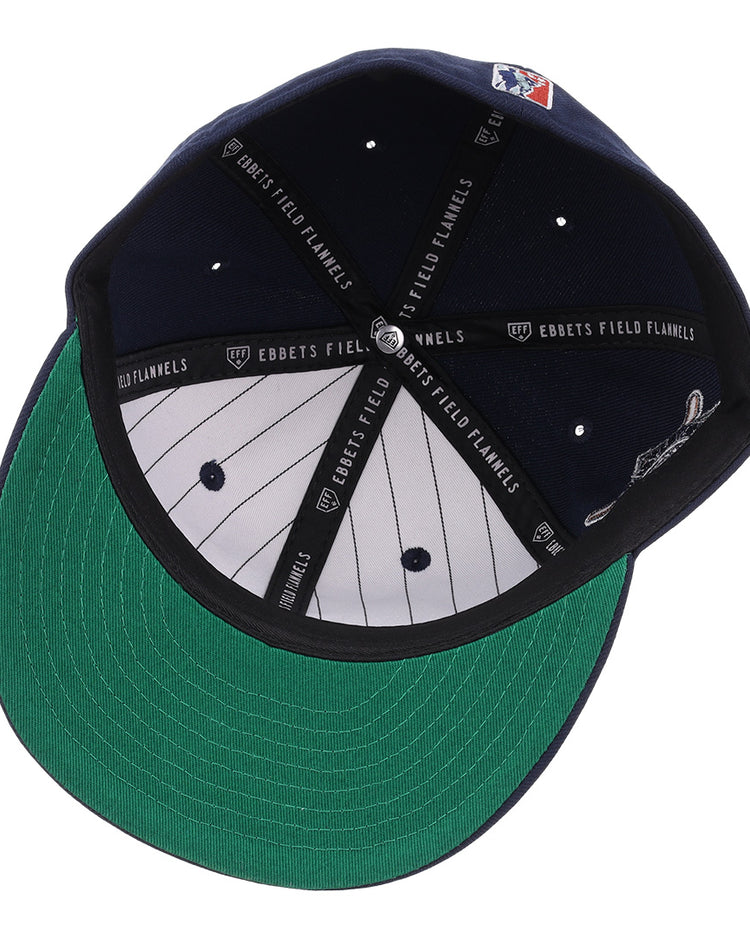 The EFF Homestead Grays NLB Flip Fitted Ballcap features navy blue fabric, a green underbrim, white pinstriped lining, black taping labeled EBBETS FIELD FLANNELS, a small MLB logo on the back, and is inspired by Pittsburgh’s Homestead Grays.