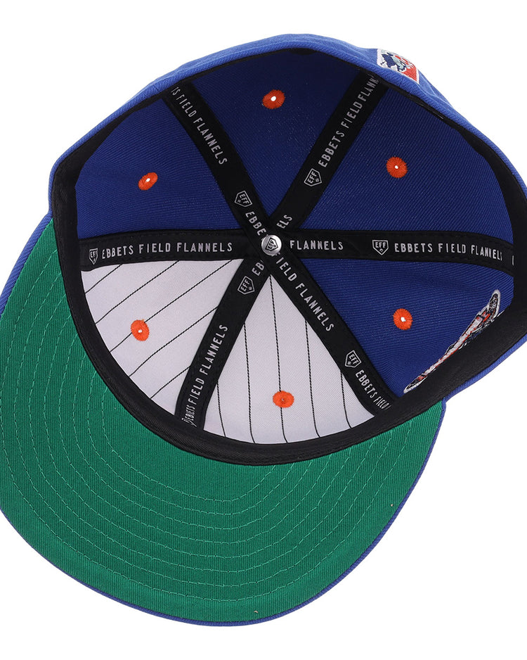 The Brooklyn Royal Giants NLB Flip Fitted Ballcap by EFF features a royal blue design, green underbrim, striped inner lining with orange dots, black EBBETS FIELD FLANNELS bands, and a vintage-inspired look.