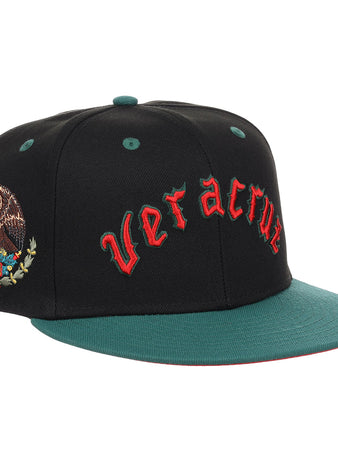 The EFF Veracruz Azules NLB Flip Fitted Ballcap is a black and green cap with “Veracruz” in red front embroidery, the Mexican emblem on the side, honoring the legacy of the Mexican League.