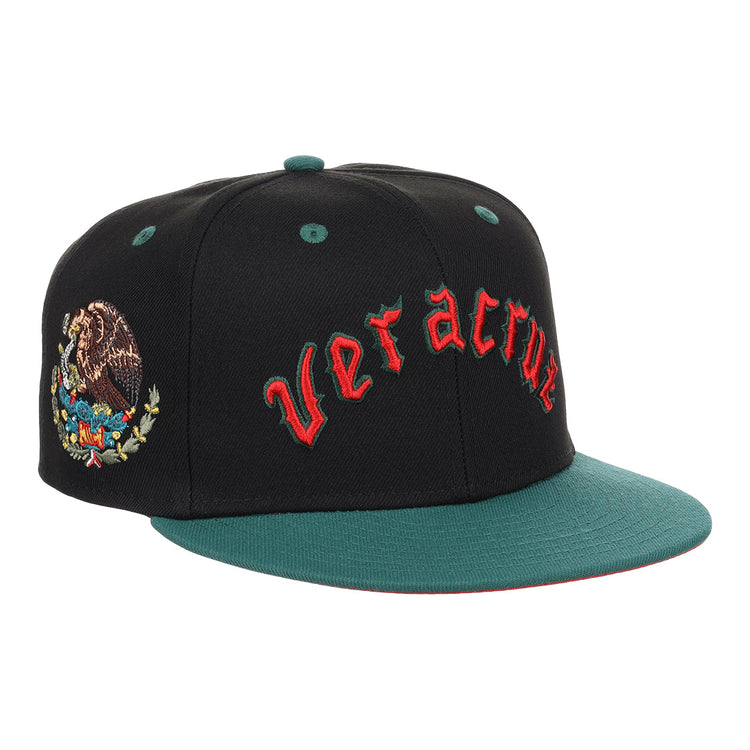 The EFF Veracruz Azules NLB Flip Fitted Ballcap is a black and green cap with “Veracruz” in red front embroidery, the Mexican emblem on the side, honoring the legacy of the Mexican League.