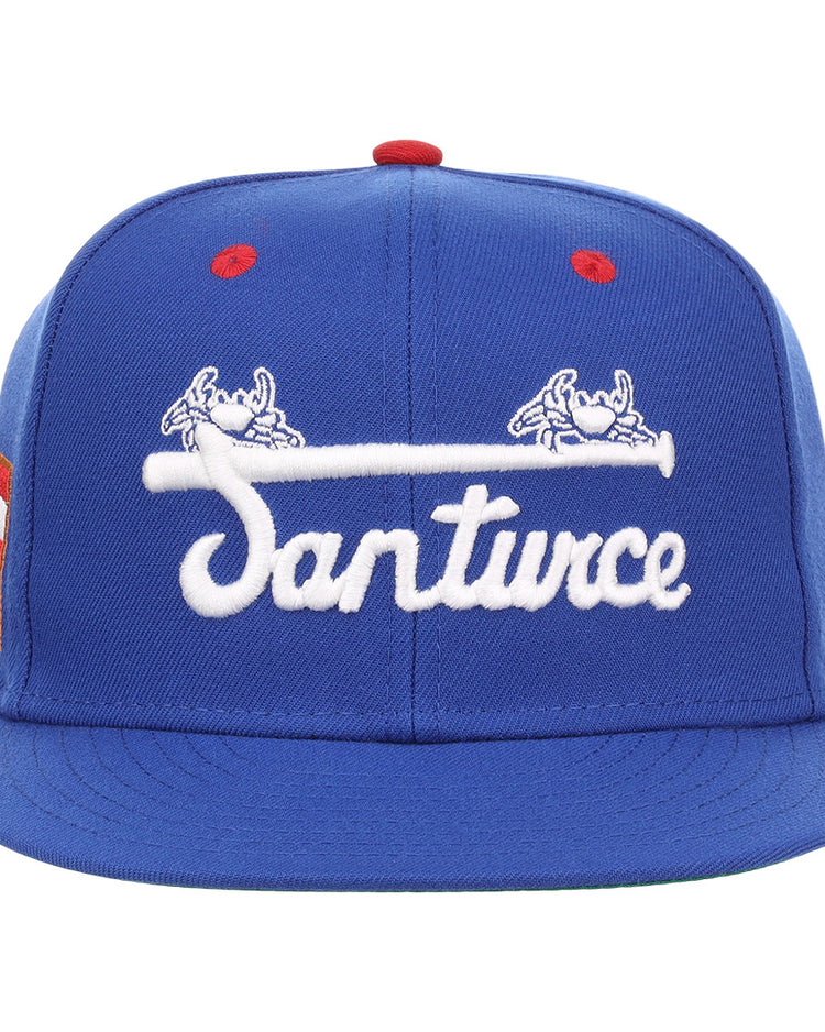 The EFF Santurce Cangrejeros NLB Flip Fitted Ballcap is a blue cap with Santurce in white, two crab designs above the name, a red top button, and three red stripes on the left side, inspired by the Puerto Rican League.