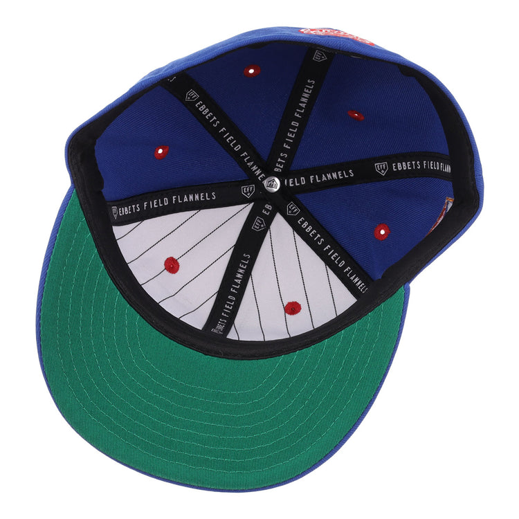 The image shows the inside of the Santurce Cangrejeros NLB Flip Fitted Ballcap by EFF, featuring a blue crown, green underbill, red stitch dots, black EFF-labeled taping, and thin black stripes—details inspired by classic Puerto Rican League styles.