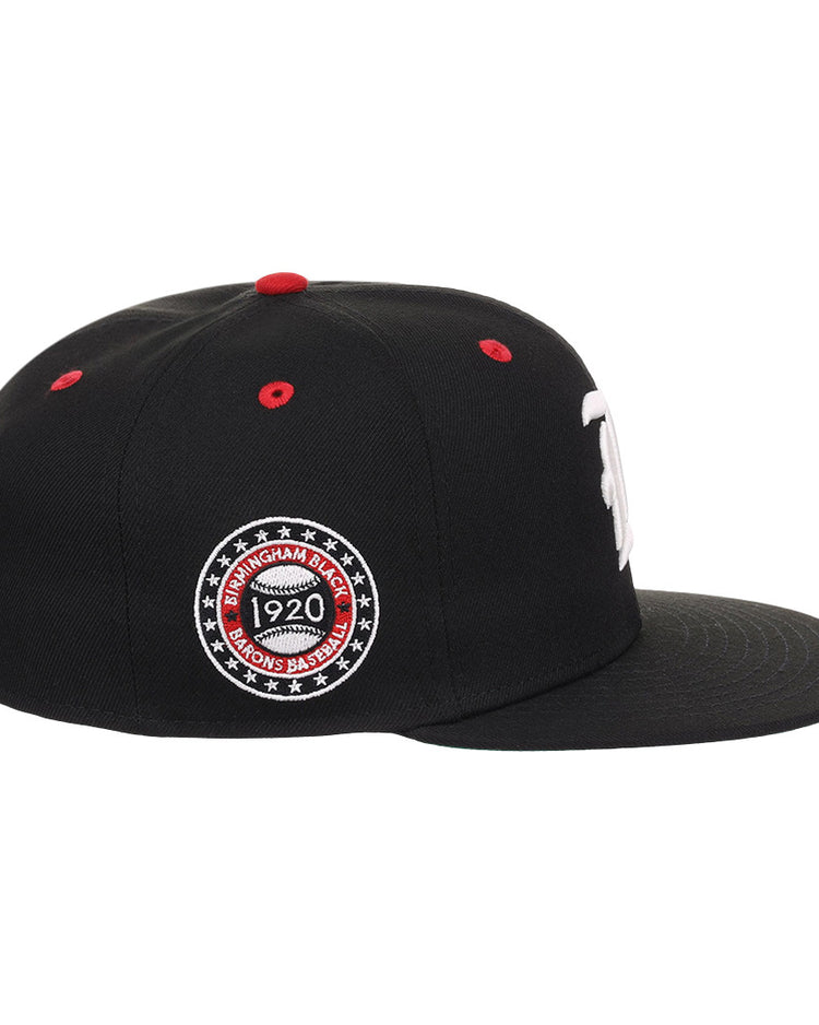 The EFF Birmingham Black Barons NLB Flip Fitted Ballcap is a black hat with a flat brim, red top button, red stitched air holes, and a circular Birmingham Black Barons 1920 patch honoring the Negro National League.