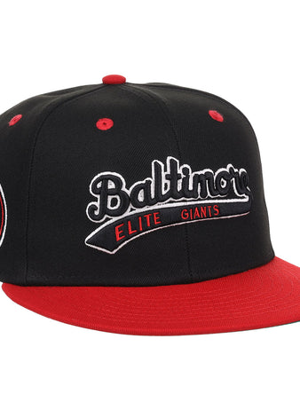 The EFF Baltimore Elite Giants NLB Flip Fitted Ballcap features black and red colors, a red bill and top button, front “Baltimore Elite Giants” embroidery, and a round Negro National League patch with a red baseball on the side.