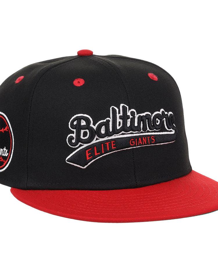 The EFF Baltimore Elite Giants NLB Flip Fitted Ballcap features black and red colors, a red bill and top button, front “Baltimore Elite Giants” embroidery, and a round Negro National League patch with a red baseball on the side.