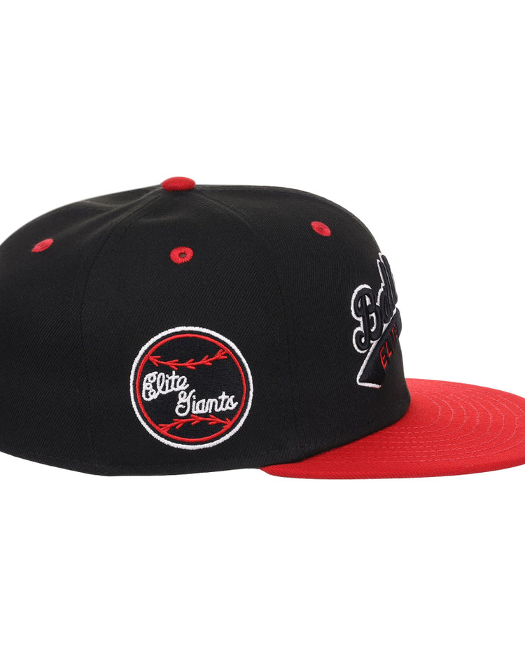 The EFF Baltimore Elite Giants NLB Flip Fitted Ballcap is a vintage-style black cap with a red brim, featuring embroidered logos and an Elite Giants patch—a classic tribute to Negro National League baseball.