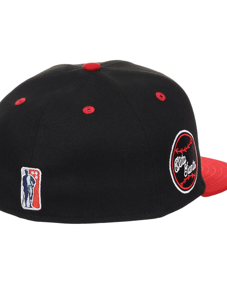 The EFF Baltimore Elite Giants NLB Flip Fitted Ballcap features a black crown, red brim and button, a circular side patch with white and red embroidery inspired by the Negro National League, and a small embroidered batter logo on the back.