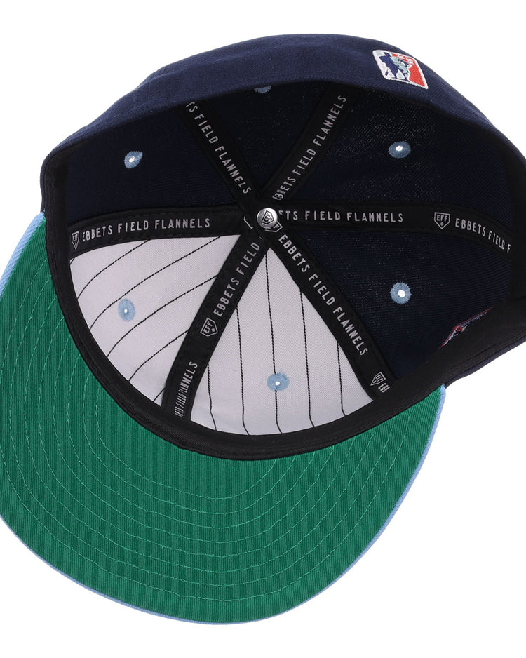 The inside of the Chicago American Giants NLB Flip Fitted Ballcap by EFF shows a navy cap with green underbill, black headband reading “EBBETS FIELD FLANNELS,” white pinstripe lining, and a stitched logo—perfect for fans.