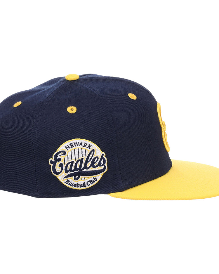 The EFF Newark Eagles NLB Flip Fitted Ballcap is a navy and yellow cap with a yellow brim, featuring an embroidered side patch reading Newark Eagles Baseball Club, honoring the Negro National League legacy.