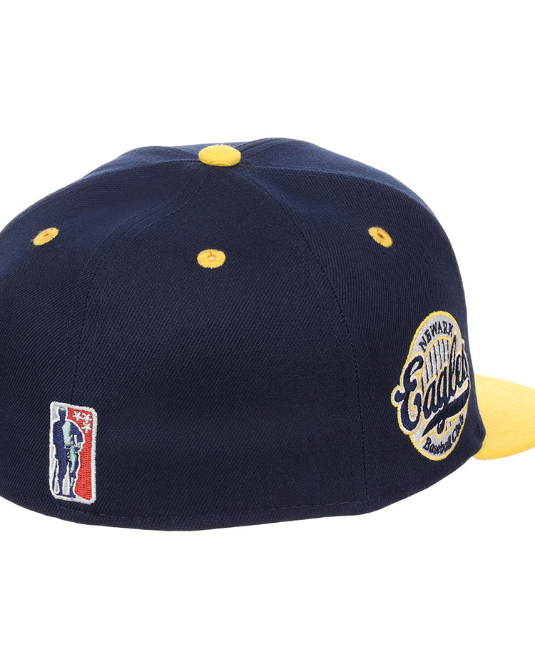 The EFF Newark Eagles NLB Flip Fitted Ballcap features a navy blue and yellow design, yellow button and eyelets, an embroidered Eagles patch on the side, and a Negro National League logo above the back opening.