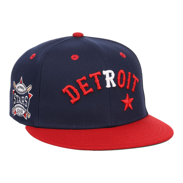 The EFF Detroit Stars NLB Flip Fitted Ballcap features a navy blue crown, red brim, DETROIT in red and white letters, a red star, and a Detroit Stars 1919 side patch—vintage style honoring the Negro National League.