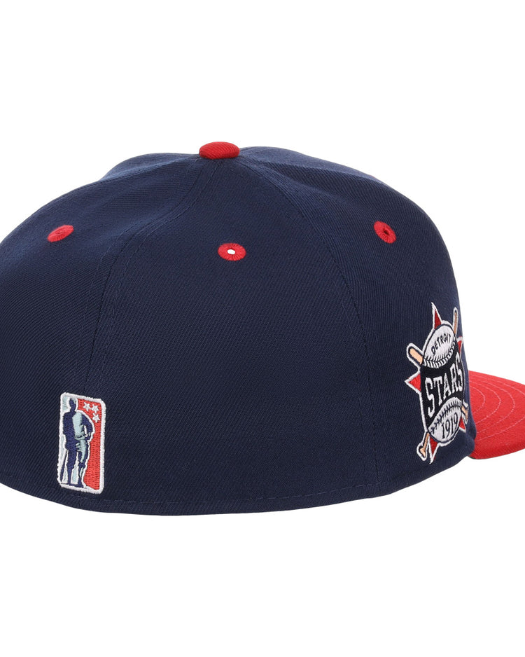 The EFF Detroit Stars NLB Flip Fitted Ballcap is a vintage-inspired navy cap with red eyelets and brim, featuring a 1974 All-Star Game patch on the side plus an embroidered silhouette logo on the back.