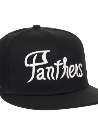 The EFF Montreal Black Panthers NLB Flip Fitted Ballcap is a vintage-inspired black cap with Panthers in bold white script on the front and a small embroidered black panther head with red eyes and mouth on the side.