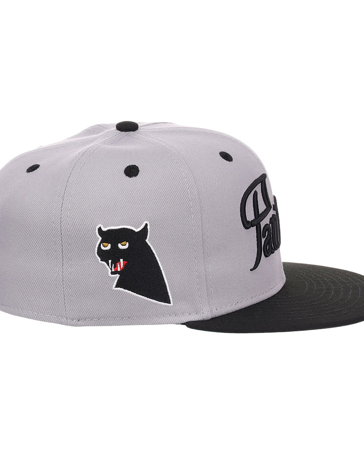 The EFF Montreal Black Panthers NLB Flip Fitted Ballcap in gray features a black brim, an embroidered black panther head with red fangs on the side, and stylized black lettering on the front for a vintage look.