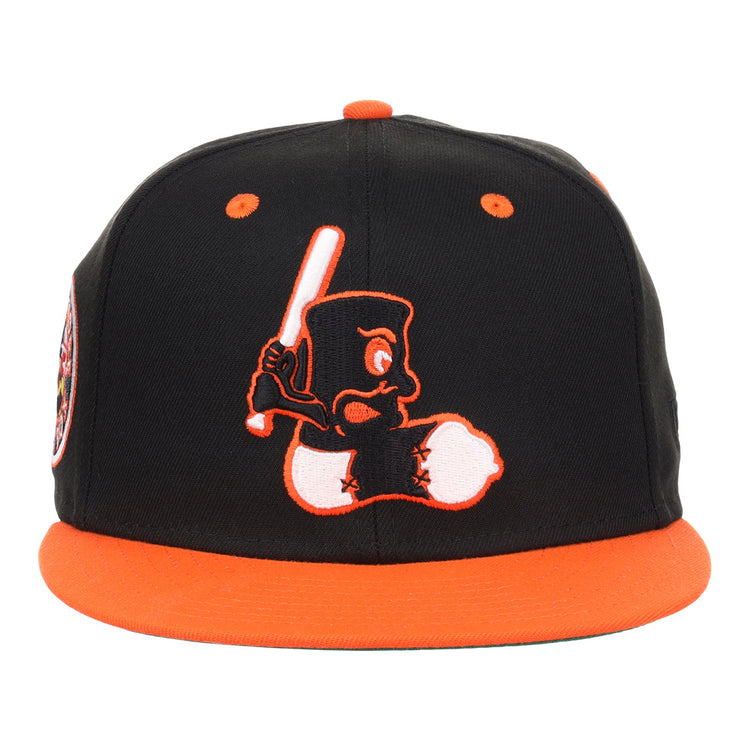 The EFF Baltimore Black Sox NLB Flip Fitted Ballcap features black and orange colors, a cartoon character with a bat embroidered on the front, and vintage-inspired orange brim and button for a standout look.