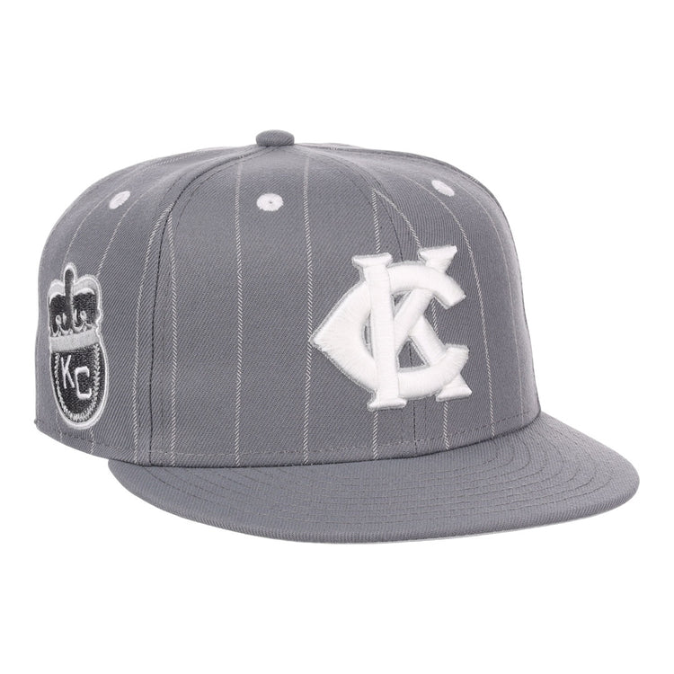 The EFF Kansas City Monarchs NLB Black Pinstripe Fitted Ballcap features white pinstripes, a white KC logo, a Negro National League-inspired side patch, flat brim, button top, and classic Monarchs baseball style accents.