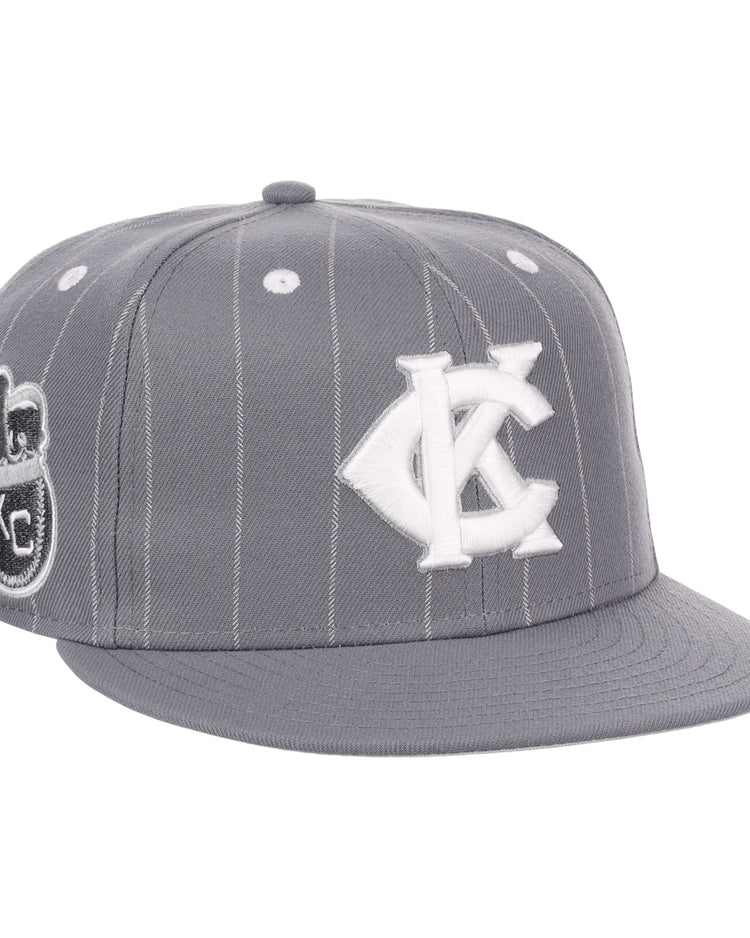 The EFF Kansas City Monarchs NLB Black Pinstripe Fitted Ballcap features white pinstripes, a white KC logo, a Negro National League-inspired side patch, flat brim, button top, and classic Monarchs baseball style accents.