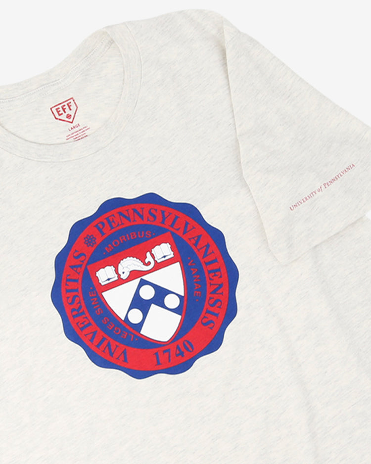 The EFF University of Pennsylvania T-Shirt in natural features the Penn crest in red and blue, with Universitas Pennsylvaniensis 1740 encircling it, inspired by legendary football star and NFL Draft pick Chuck Bednarik.