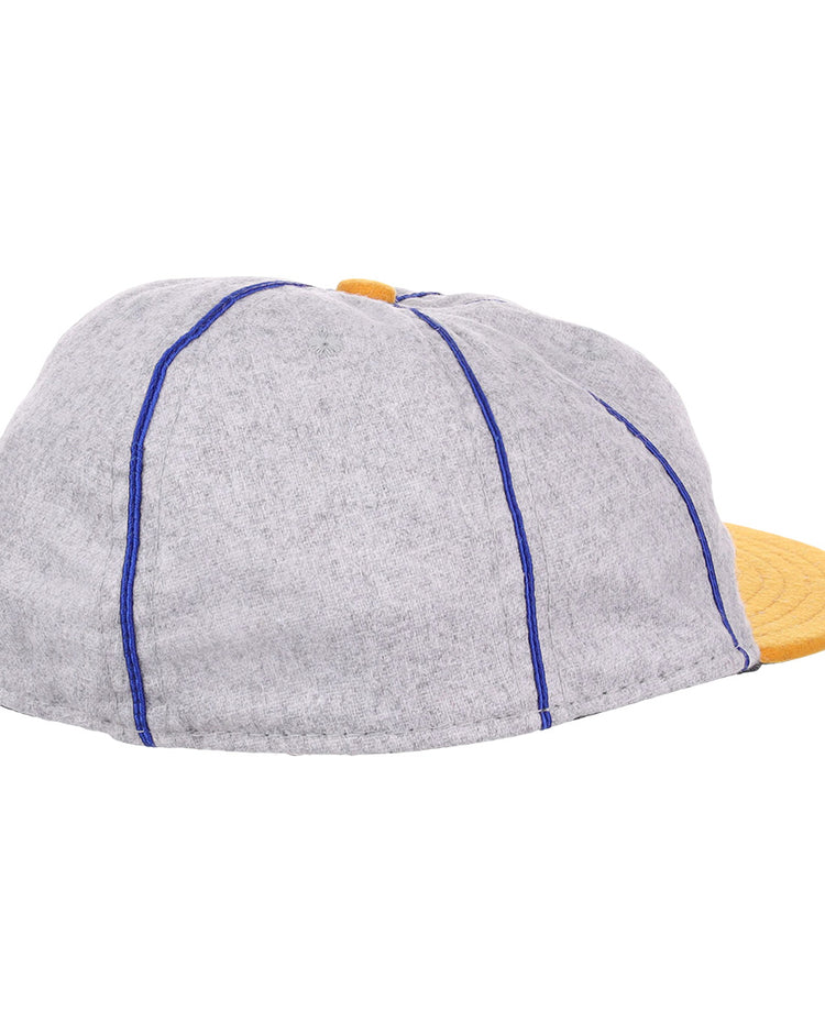 The EFF Pasadena Merchants 1919 Vintage 8-Panel Ballcap features a grey wool finish, blue stitching, and a yellow brim. Inspired by classic California Winter League styles, it’s shown here from a side and rear angle.