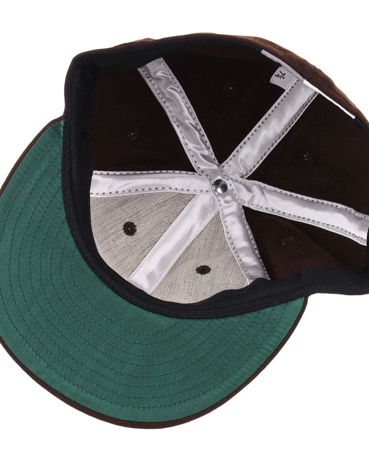 An upside-down view of the EFF Independent Subway System 1939 Vintage Ballcap showcases its green visor, black interior panels, silver inner lining, and black stitched eyelets—classic details from the original New York transit hat design.