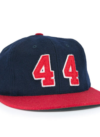 The Ebbets Field Flannels Hank Aaron 1957 Signature Series Ballcap is a vintage-style wool cap in navy with a red brim and bold red-and-white “44” on the front, inspired by baseball legends and proudly made in the USA.
