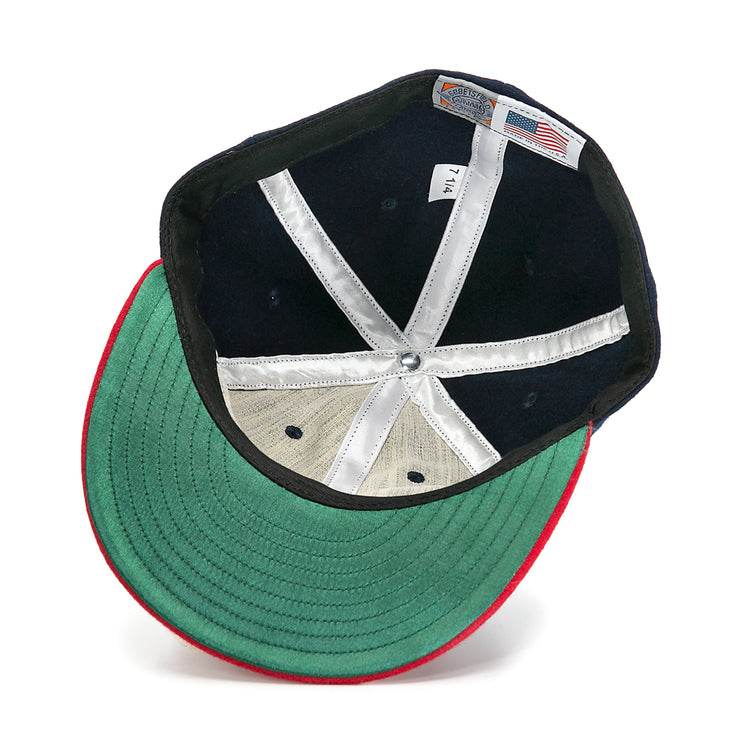 An inside view of the Ebbets Field Flannels Hank Aaron 1957 Signature Series Ballcap shows a green underbrim, red trim, white stitched panels, silver top button, and an American flag tag, highlighting its USA-made quality.