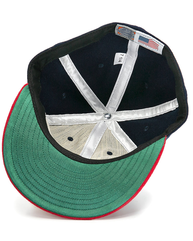 An inside view of the Ebbets Field Flannels Hank Aaron 1957 Signature Series Ballcap shows a green underbrim, red trim, white stitched panels, silver top button, and an American flag tag, highlighting its USA-made quality.