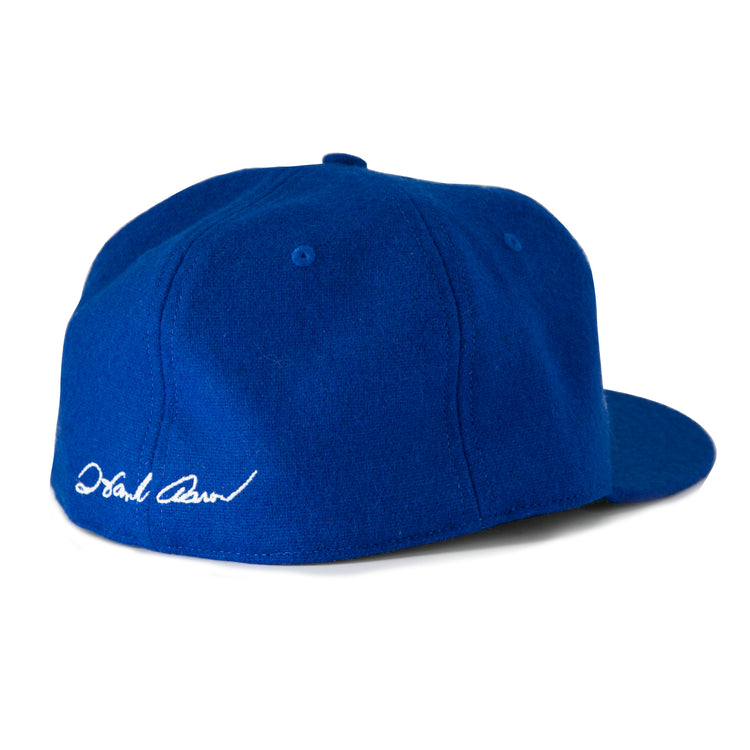 The Hank Aaron 1973 Signature Series Ballcap by Ebbets Field Flannels is a royal blue vintage wool cap, made in the USA, shown from the back left with a white embroidered signature above the brim.