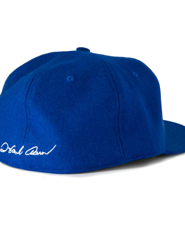 The Hank Aaron 1973 Signature Series Ballcap by Ebbets Field Flannels is a royal blue vintage wool cap, made in the USA, shown from the back left with a white embroidered signature above the brim.