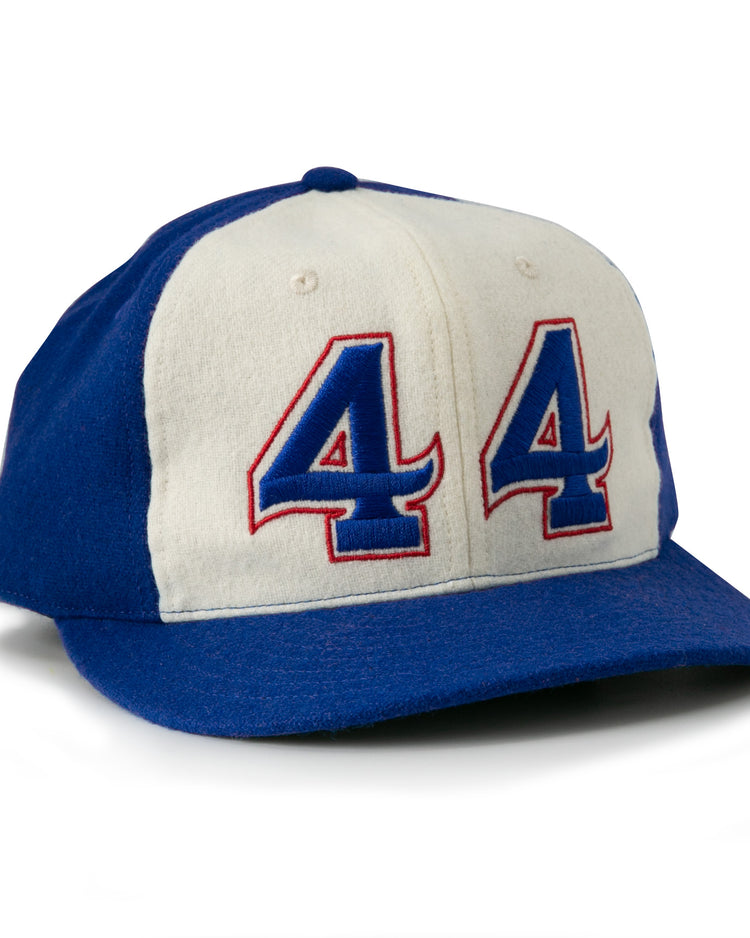 The Hank Aaron 1973 Signature Series Ballcap by Ebbets Field Flannels is a vintage-style wool cap, made in the USA, featuring blue/white panels and “44” in blue and red outlined on the front.