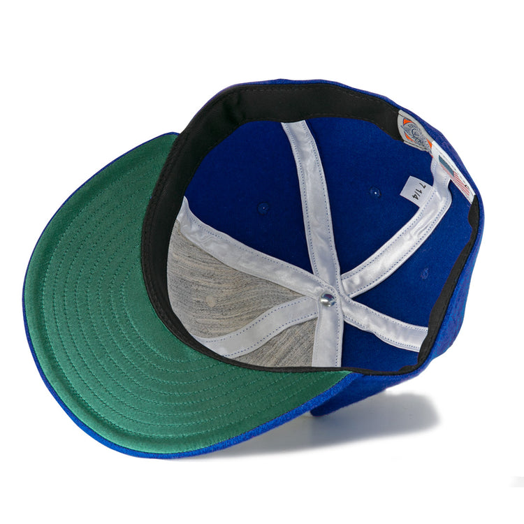 The Hank Aaron 1973 Signature Series Ballcap by Ebbets Field Flannels is a blue vintage wool cap shown from below, highlighting its green under-brim, white hatband, and inner structure with a central metal button.