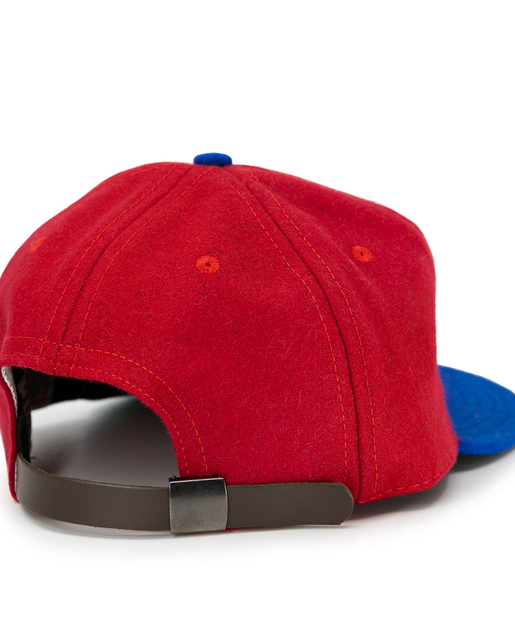 The EFF Alaska Goldpanners 1964 Vintage Ballcap is red with a blue brim, shown from the back. It features an adjustable brown strap with metal clasp—an authentic reproduction of the original team cap.