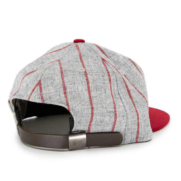 The Ebbets Field Flannels Club Artemisa 1943 Vintage Ballcap, made of genuine wool, features a bold red brim, grey panels with red stripes, and a brown adjustable strap with metal buckle—shown from the back.