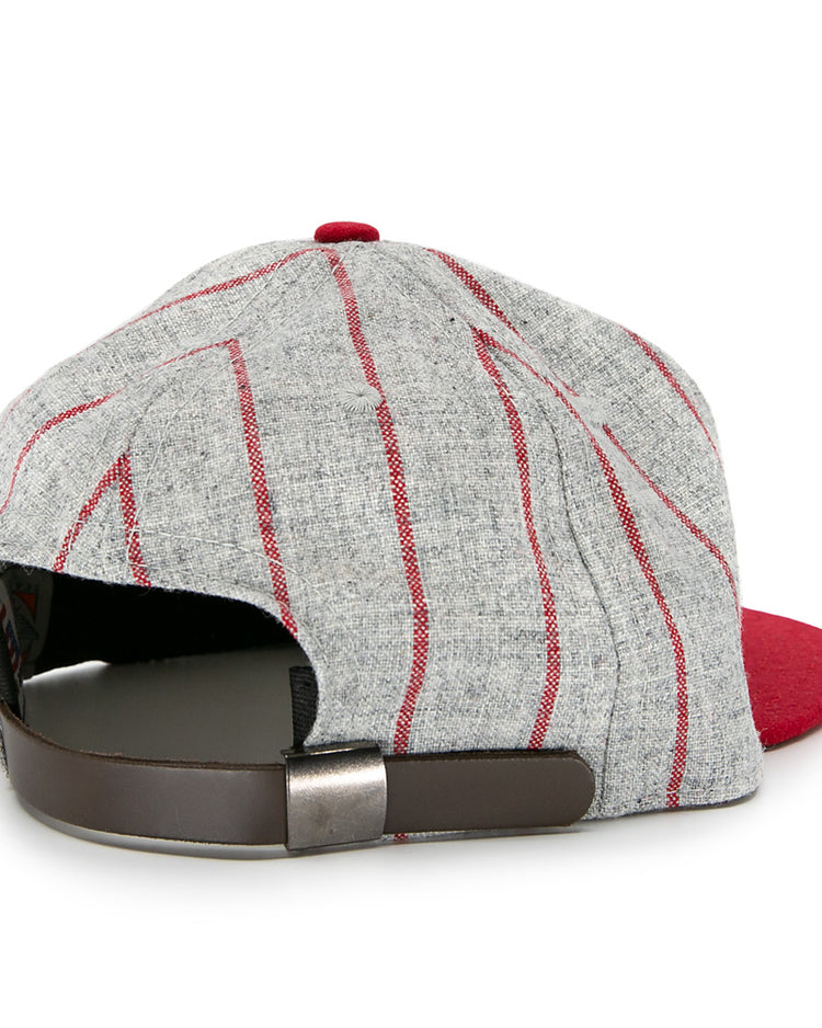 The Ebbets Field Flannels Club Artemisa 1943 Vintage Ballcap, made of genuine wool, features a bold red brim, grey panels with red stripes, and a brown adjustable strap with metal buckle—shown from the back.