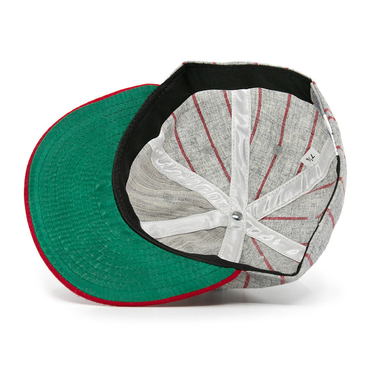 An overhead shot of the Ebbets Field Flannels Club Artemisa 1943 Vintage Ballcap, a wool cap with red stripes, green underside brim, and white interior seams. The hat is shown upside down to highlight its inner structure and tag.