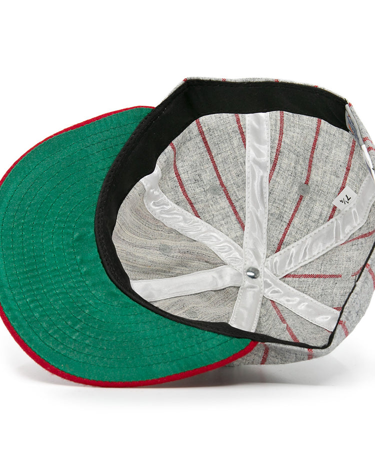 An overhead shot of the Ebbets Field Flannels Club Artemisa 1943 Vintage Ballcap, a wool cap with red stripes, green underside brim, and white interior seams. The hat is shown upside down to highlight its inner structure and tag.