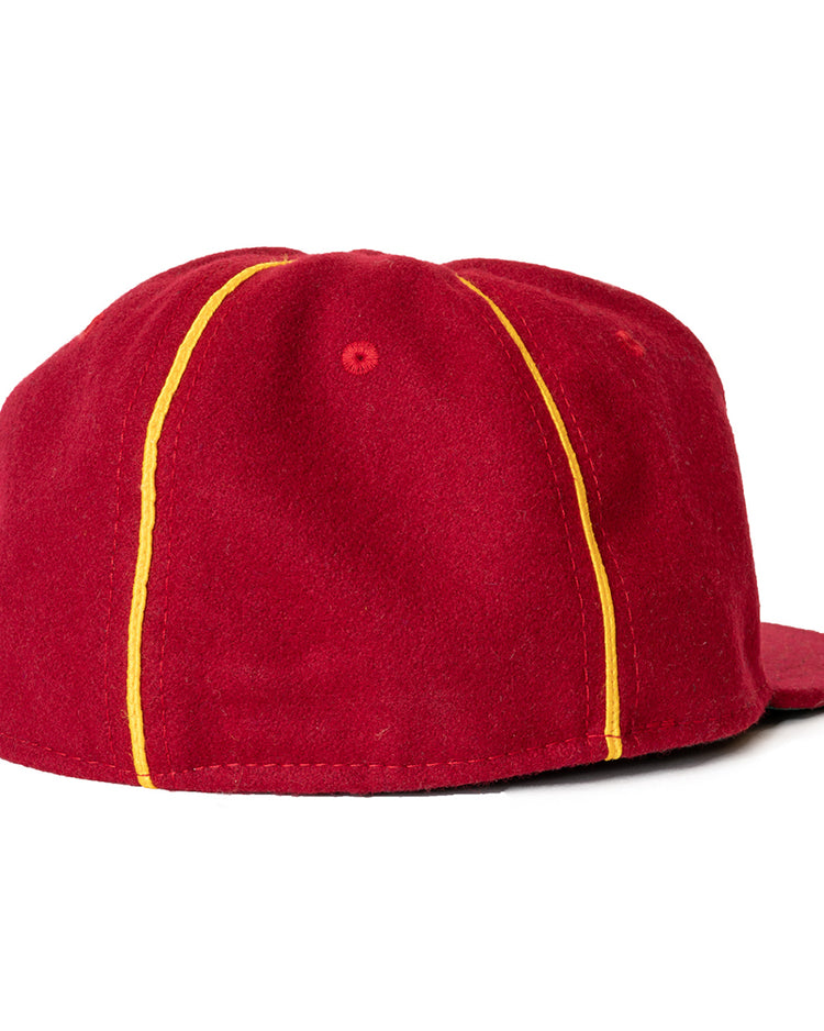 The Ebbets Field Flannels Club Bacardi 1930 Vintage Ballcap is a red wool cap with a flat brim and two yellow stripes from brim to back, inspired by the Cuban National Amateur League. Shown from the back.