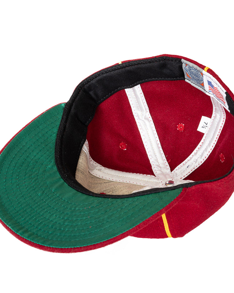 A red Club Bacardi 1930 Vintage Ballcap by Ebbets Field Flannels is shown upside down, displaying the green underside of the brim, white inner lining, and a size tag marked 7 1/4 next to an American flag label.