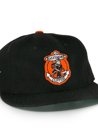 The EFF Baltimore Clippers 1962 Vintage Ballcap is a black wool cap with the team’s sailor-and-hockey-stick logo on front, an EHL shield embroidered on the side, and an orange top button.