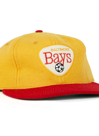 The Baltimore Bays 1967 Vintage Ballcap by EFF features a yellow crown, red brim, and a white front patch with “Baltimore Bays” text and soccer ball graphic, inspired by the authentic 1967 design.