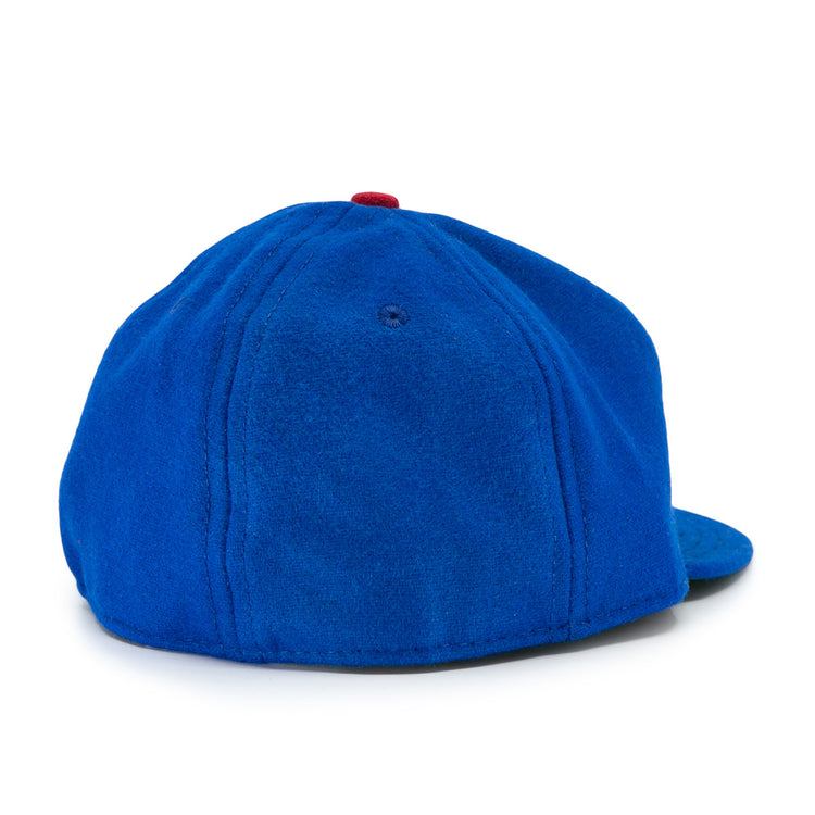 The Los Barbudos 1959 Vintage Ballcap by EFF is a blue wool baseball cap with a curved brim, visible stitching, smooth fabric, and a small red button on top, seen from the back.