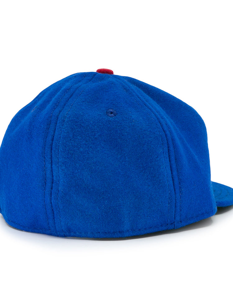 The Los Barbudos 1959 Vintage Ballcap by EFF is a blue wool baseball cap with a curved brim, visible stitching, smooth fabric, and a small red button on top, seen from the back.