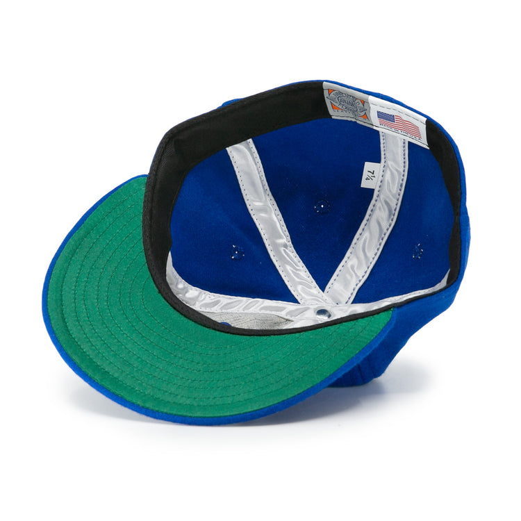 The EFF Los Barbudos 1959 Vintage Ballcap is shown upside down, revealing its green underbrim, white interior lining, tags, and detailed stitching inside the crown.