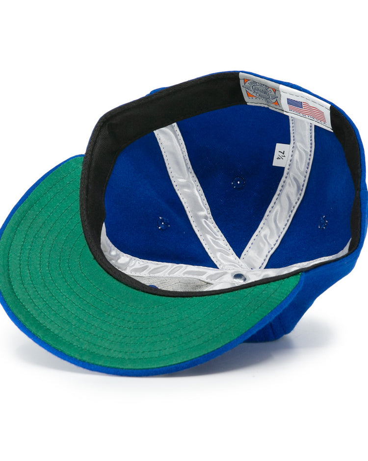 The EFF Los Barbudos 1959 Vintage Ballcap is shown upside down, revealing its green underbrim, white interior lining, tags, and detailed stitching inside the crown.