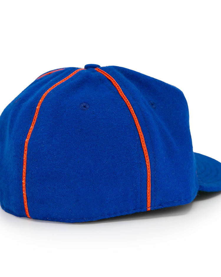 The EFF Boston Bloomer Girls 1910 Vintage Ballcap is a blue baseball cap with a curved brim and two orange stripes down the back, inspired by classic women’s baseball and reminiscent of early 20th-century style.